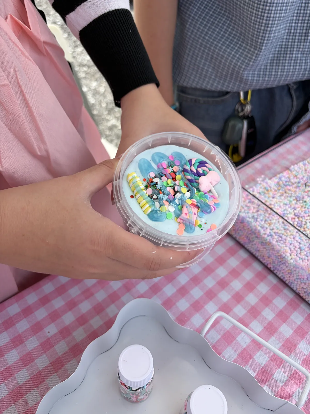 A finished cup of blue slime loaded with sprinkles and candy charms